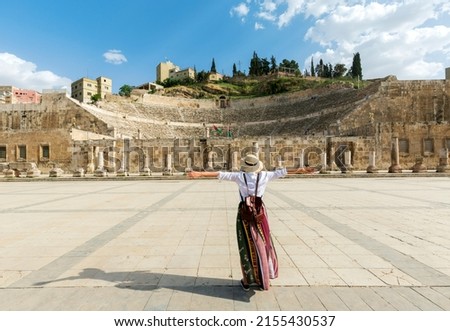 Amman, jordan - young girl with hat standing with open arms looking  Roman Theater one of the most important tourist attractions in Amman, Jordan. Royalty-Free Stock Photo #2155430537