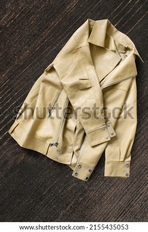 Folded yellow leather jacket on dark brown wooden background