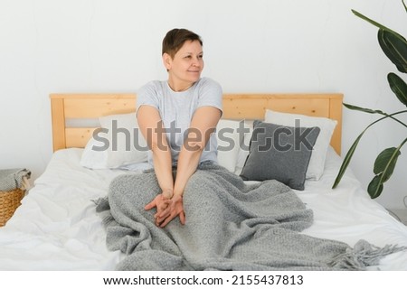 Happy fresh beautiful mature older woman awake after healthy sleep stretch wake up in cozy comfortable bed, smiling middle aged lady enjoy good morning looking at camera, close up portrait, top view