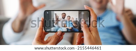 Close up of female hands taking picture with mobile phone of happy father and son sitting on a couch
