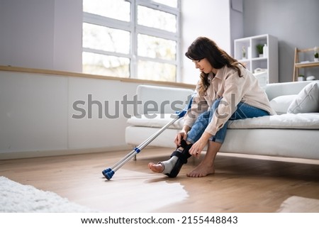Woman With Leg Injury Using Crutches At Home Royalty-Free Stock Photo #2155448843