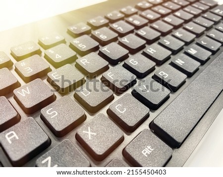 A black keyboard in the sunlight. Keyboard keys with white letters. Writing text on the keyboard.