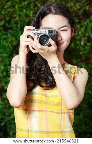 Asian woman happily using a retro camera