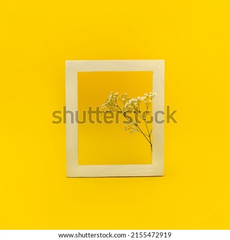 Layout made with flowers on a yellow background with frame and copy space. Creative minimal spring or summer concept.