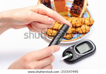 Woman doing test for determination level sugar, glucose meter and fresh baked pastry on colorful plate in background, concept for diabetes and glucose level test