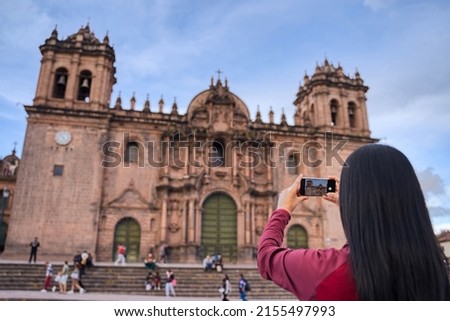 Tourist with his back turned taking a picture with your mobile of the cathedral of Cuzco