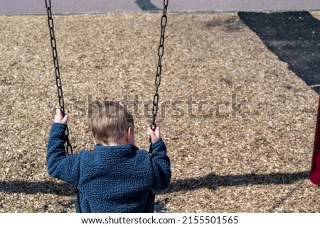 Preschool Caucasian boy on a swing over a woodchip base. Royalty-Free Stock Photo #2155501565