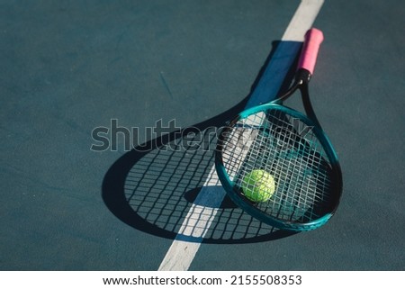 High angle view of tennis racket and ball with shadow by line on blue court during sunny day. unaltered, sport and tennis game concept.