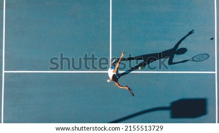 Overhead view of african american young female player serving on blue tennis court during sunny day. unaltered, sport, competition and tennis game concept. Royalty-Free Stock Photo #2155513729