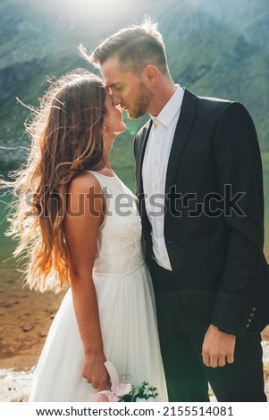 Young married people posing on the background of a lake standing close to each other, head to head. Holiday wedding. A ceremony outdoors. Close-up portrait