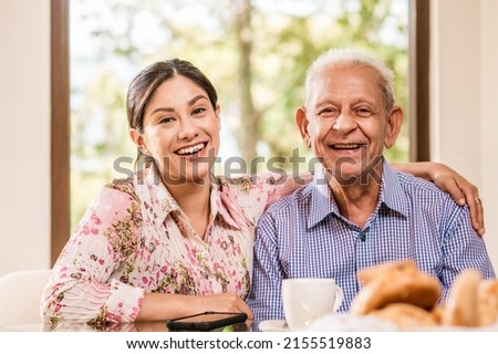 Portrait of a smiling senior father with his beautiful older daughter looking at the camera, happy mature man and young beautiful latin woman. Royalty-Free Stock Photo #2155519883