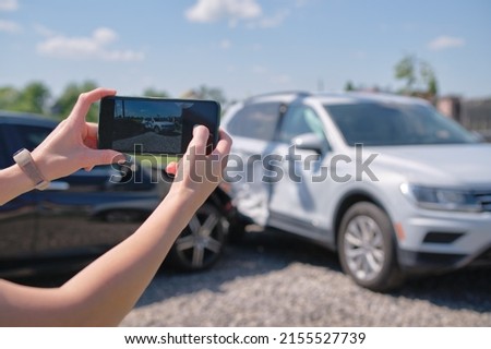 Stressed driver taking picture on sellphone camera of smashed vehicle calling for emergency service help after car accident. Road safety and insurance concept