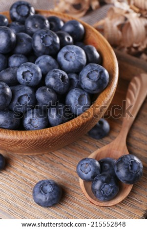 Wooden bowl of blueberries on cutting board on sacking napkin closeup
