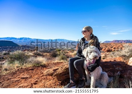 Happy woman on an outdoor hike with her dog. Enjoying nature on a sunny day. Enjoying a scenic overlook in St. George, Utah Royalty-Free Stock Photo #2155551795