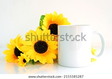 White coffee mug blank mockup with bouquet of yellow sunflowers, copyspace.