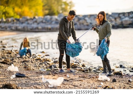 Group of volunteers cleaning beach on sunny day Royalty-Free Stock Photo #2155591269
