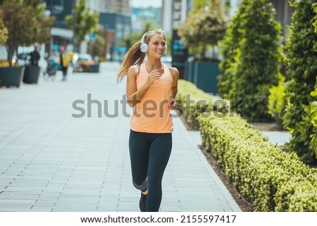 Woman running. Female runner jogging, training for marathon. Fit girl fitness athlete model exercising outdoor. Photo of young woman running on sidewalk in morning. Health conscious concept 