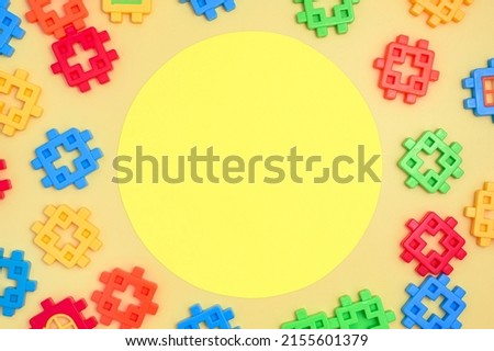 Poster for decorative design. Decorative yellow round kids template frame on kids colourful plastic designer set collection. Top view. Flatlay, copyspace for text