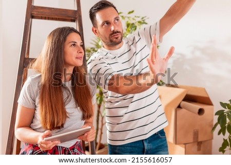 Couple in love having fun while moving in new home, searching for apartment redecoration ideas using tablet computer Royalty-Free Stock Photo #2155616057