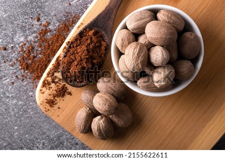 Nutmeg macro in a bowl. Nutmeg powder. Nutmeg spice in a wooden spoon. Royalty-Free Stock Photo #2155622611