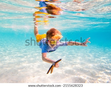 Child snorkeling. Kids swim underwater. Beach and sea summer vacation with children. Little boy watching coral reef fish. Marine life on exotic island. Kid swimming and diving with snorkel and mask.