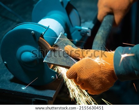 man sharpening an ax blade on a grinder Royalty-Free Stock Photo #2155630451