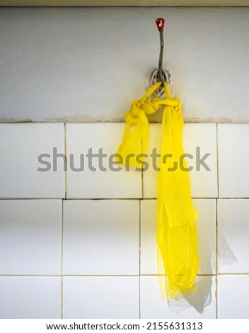 A yellow washcloth hanging on the bathroom wall.