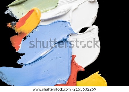 colorful abstract background from smears of oil paint on black palette