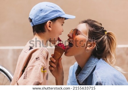 Woman with her son enjoying family time walking in the city together on a sunny day, eating ice cream. Happy family parent with little child boy kid enjoy outdoor lifestyle. Mum and sun lick gelato. Royalty-Free Stock Photo #2155633715