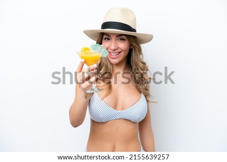 Young woman holding cocktail and wearing a bikini isolated on white background with happy expression