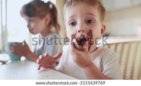 children eat chocolate. dirty little baby kids in lifestyle the kitchen eating chocolate in the morning. happy family eating sweets kid dream concept. baby dirty face eating chocolate cocoa Royalty-Free Stock Photo #2155639769