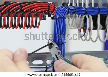 Cutting the cable tie on the insulated mounting wire in the electrical panel. Royalty-Free Stock Photo #2155651619