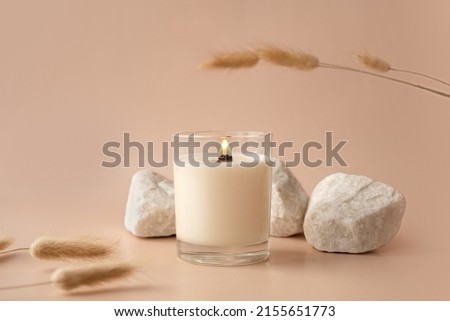 Vanilla burning candle on beige background. Warm aesthetic composition with stones and dry flowers. Home comfort, spa, relax and wellness concept. Interior decoration Royalty-Free Stock Photo #2155651773
