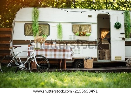 Camping season. Photo studio. Trailer on the background of the forest. Bicycle on the background of the trailer