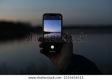 hand holding smart phone and taking photo of beautiful sunset