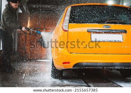 Washing a yellow car at a contactless self-service car wash. Washing a sedan car with foam and high-pressure water. Spring cleaning at the car wash. Royalty-Free Stock Photo #2155657385