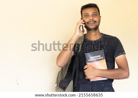 Portrait of teenager college student holding mobile phone of Indian origin.