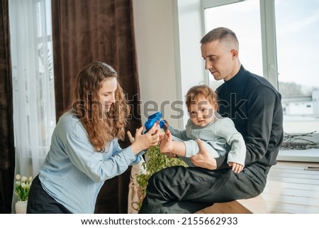 mom and dad put shoes on the baby. High quality photo