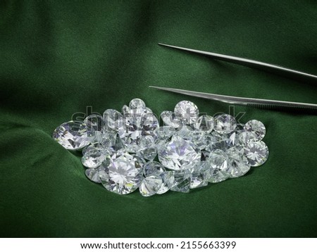Loose Diamonds on Green Silk Background. Ethical Diamond Themed Photograph with Diamond Sorting Tweezers.  Royalty-Free Stock Photo #2155663399