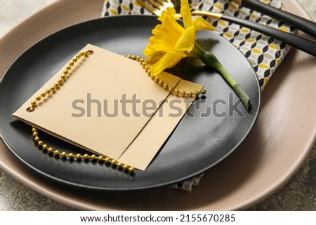 Table setting with blank card and narcissus flower, closeup