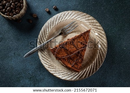 Plate with slice of tasty homemade chocolate cake on blue background. Space for text. Cake flatlay. Piece of chocolate cake