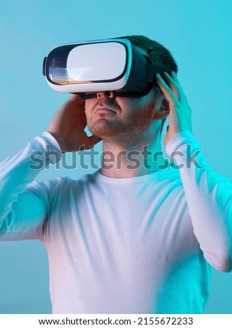 Modern young man experiencing virtual reality glasses in studio