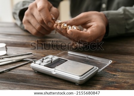 Man with jewelry and scales at table, closeup