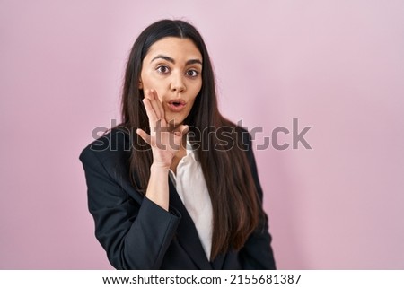 Young brunette woman wearing business style over pink background hand on mouth telling secret rumor, whispering malicious talk conversation 