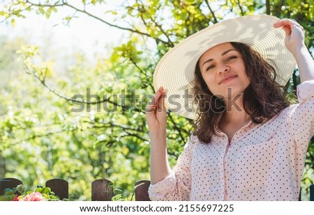 Young brown haired woman posing in sun hut looking at camera.