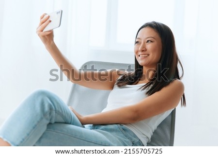 Cheerful cute happy tanned lovely young Asian woman smiling to a boyfriend on live doing selfie video call at home. Distance communication Social media concept. Cool offer Banner Wide angle