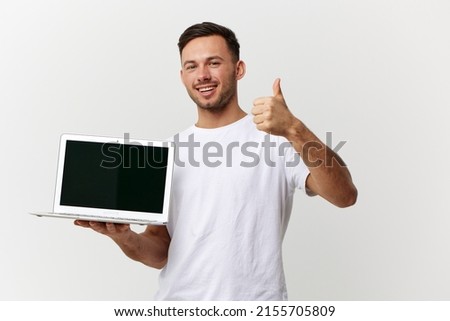 Joyful smiling tanned handsome IT professional man in white basic t-shirt hold laptop show thumb up posing isolated on white studio background. Copy space Banner Mockup. Electronics repair concept