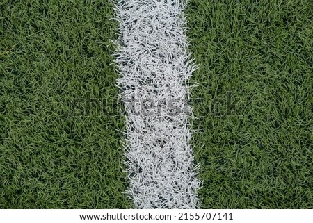Green synthetic grass sports field with white line shot from above. Sports background for product display, banner, or mockup. High quality photo