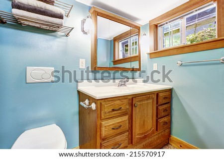 Blue bathroom interior with wooden vanity cabinet and wood window trim