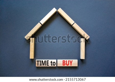 Time to buy house symbol. Concept words 'Time to buy' on wooden blocks near miniature house. Beautiful grey background, copy space. Business and time to buy house concept.